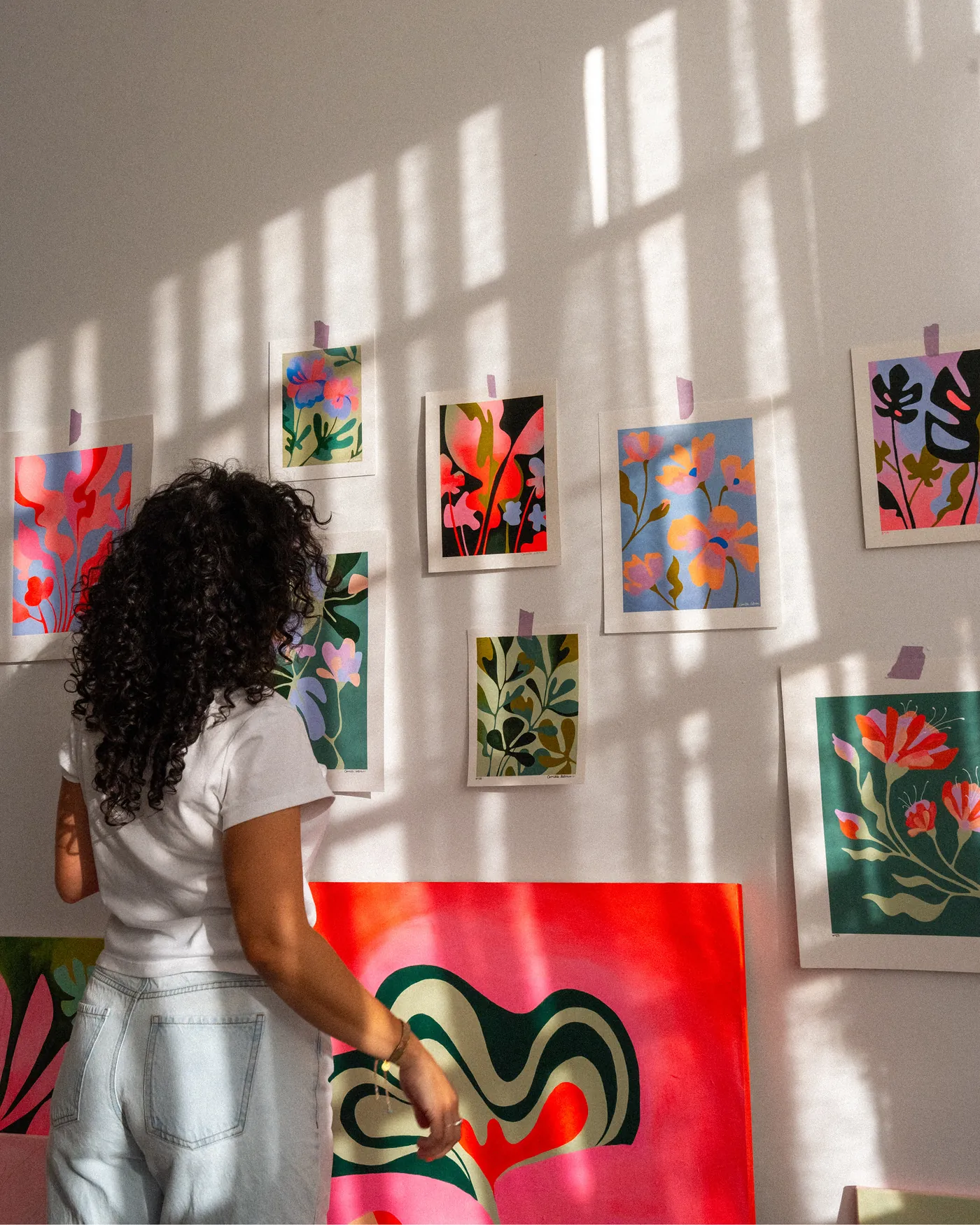 Camille LeBrun devant le mur de prints de son atelier