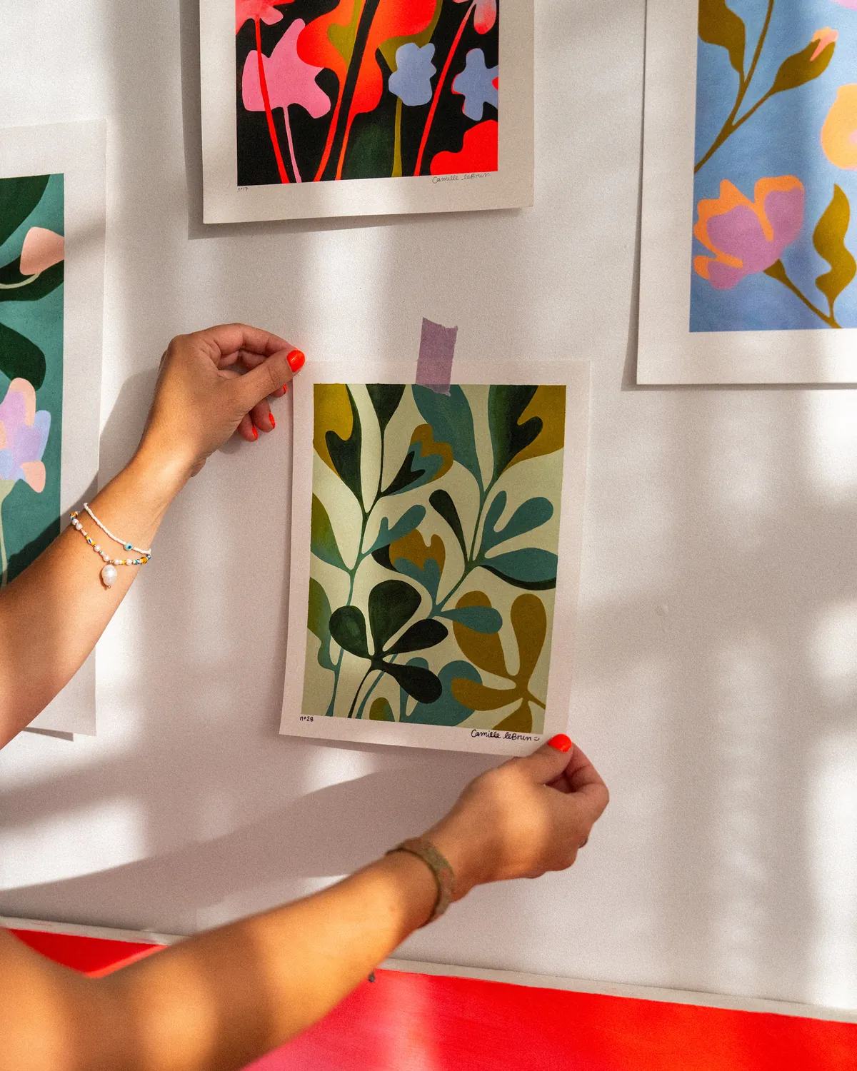 Camille accroche un print au mur de son atelier